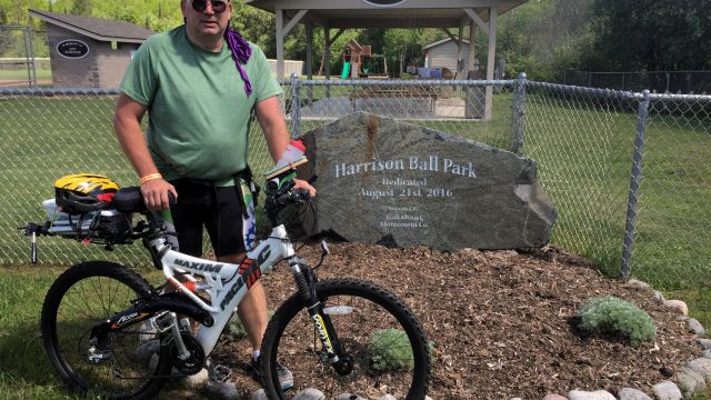 Paul and bike in front of sign