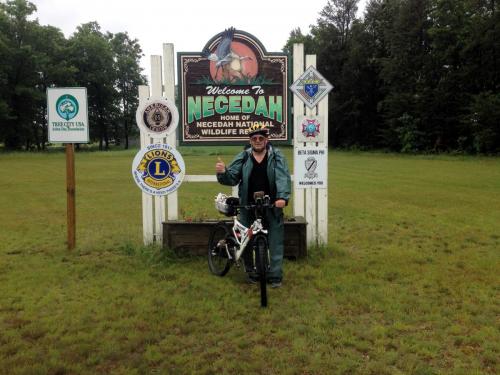 paul and bike in front of welcome to Neceedah sign.