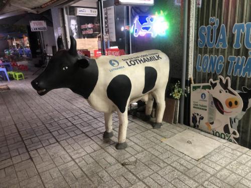 Statue of cow in front of shop.